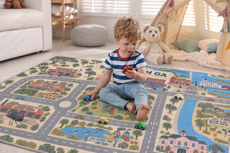 A toddler playing with toy cars on a Savannah rug